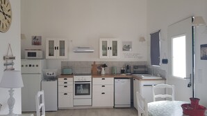 A kitchen with white cabinets, a microwave, a toaster, and a coffee maker. - Charming rentals (Mazan)