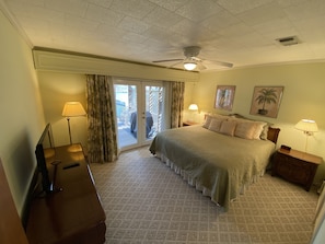 Relax in this serene space with a large bed, two bedside tables, and a ceiling fan. Enjoy access to a patio and pool.