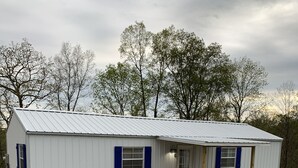 Ein kleines, eingeschossiges Gebäude mit Kiesweg und Holzterrasse.