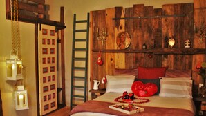 Ein gemütliches Schlafzimmer mit einem Holzkopfende, einer Leiter und einem Nachttischchen mit einer Lampe.