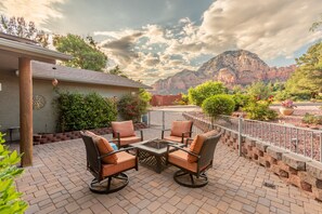 A patio with outdoor furniture, a fire pit, and a view of mountains.