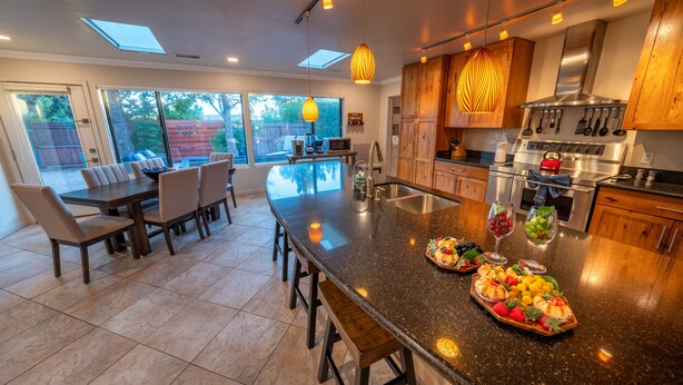 A modern kitchen with a large island, stainless steel appliances, and wooden cabinets.