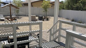 Un'area esterna riparata con un pavimento in legno, ringhiere bianche e una pergola che offre ombra.