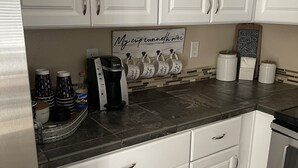 Una cucina con mobili bianchi, una macchina da caffè e una lavagna.