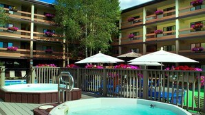 A hotel with multiple balconies, outdoor hot tubs, and lounge chairs.