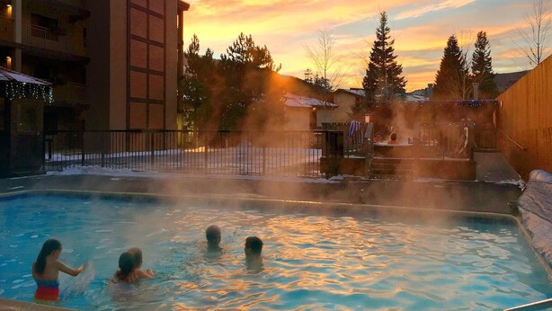 A hot tub area with a view of a sunset, surrounded by buildings and trees.