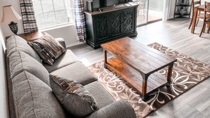 Un salon avec un canapé, une table basse en bois et un téléviseur posé sur un meuble.