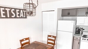 Une cuisine compacte comprenant une table à manger, des chaises, un réfrigérateur, une cuisinière et des placards.