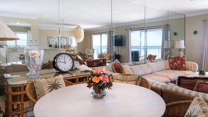 A spacious living room with a large sofa, a round table, and a clock.