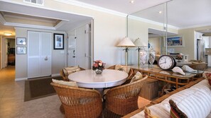 Een eethoek met rieten stoelen, een ronde tafel en een spiegel die de keuken weerspiegelt.
