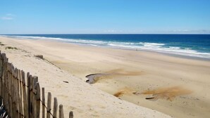 Une plage bordée d’une clôture en bois, offrant une vue dégagée sur l’océan.