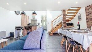 Un salon moderne comprenant un canapé, un coin repas, une cuisine et un escalier.