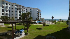 A hotel courtyard with a pool, lounge chairs, and a view of the sea. - One bedroom on the ground floor (Manilva)