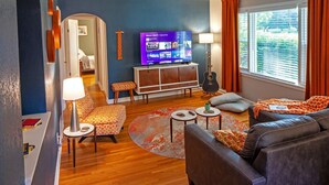 Una sala de estar con televisor, sofá y una mesita con lámpara.