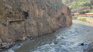 A river flowing through a rocky gorge with a bridge in the background.