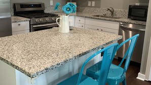 A kitchen with white cabinets, granite countertops, a stainless steel range, a microwave, and two blue bar stools. - Ample Space in Grant Park, Close to Everything! (Atlanta)