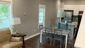 A spacious living room with a leather sofa, a dining area with a table and chairs, and a kitchen with white cabinets and stainless steel appliances. - Ample Space in Grant Park, Close to Everything! (Atlanta)