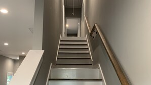 A modern staircase with white walls and dark wooden steps, leading to a landing with a door. - Ample Space in Grant Park, Close to Everything! (Atlanta)