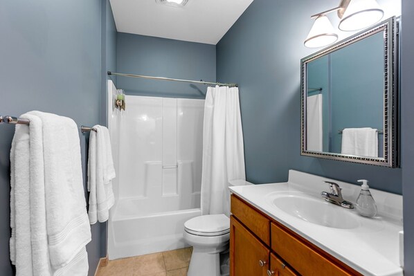 A bathroom with a bathtub, toilet, and vanity with a mirror.