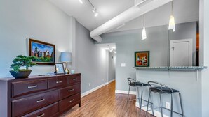 Una cocina moderna con encimera de madera, dos taburetes de bar y una zona de comedor con piso de madera.