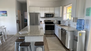 A modern kitchen with white cabinets, stainless steel appliances, and a granite countertop.
