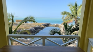 A wooden table with a view of a coastal landscape, including a body of water and palm trees.