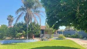 A well-maintained lawn with a variety of trees and a brick building in the background. - Town Beach Short Stay on Ormsby Terrace                   Beach across the Road. (Mandurah)