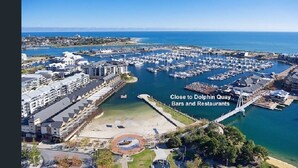 An aerial view of a marina with boats, a pier, and buildings. - Town Beach Short Stay on Ormsby Terrace                   Beach across the Road. (Mandurah)