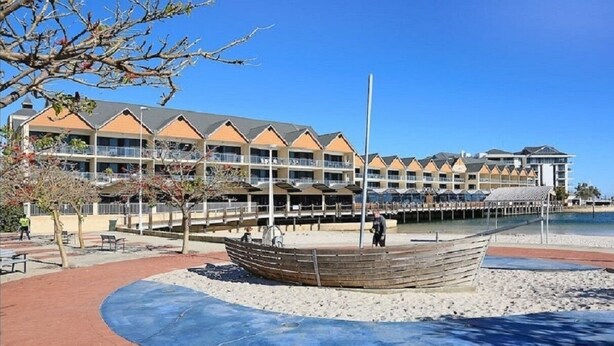 A coastal hotel with a large building, a wooden boat display, and a sandy beach area. - Town Beach Short Stay on Ormsby Terrace                   Beach across the Road. (Mandurah)