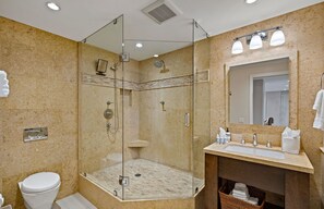 Une salle de bain moderne avec une douche à parois de verre, des toilettes blanches et un meuble-lavabo doté d’un miroir et d’un évier.