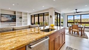 A modern kitchen with a granite countertop, a built-in dishwasher, and a dining area with a table and chairs.
