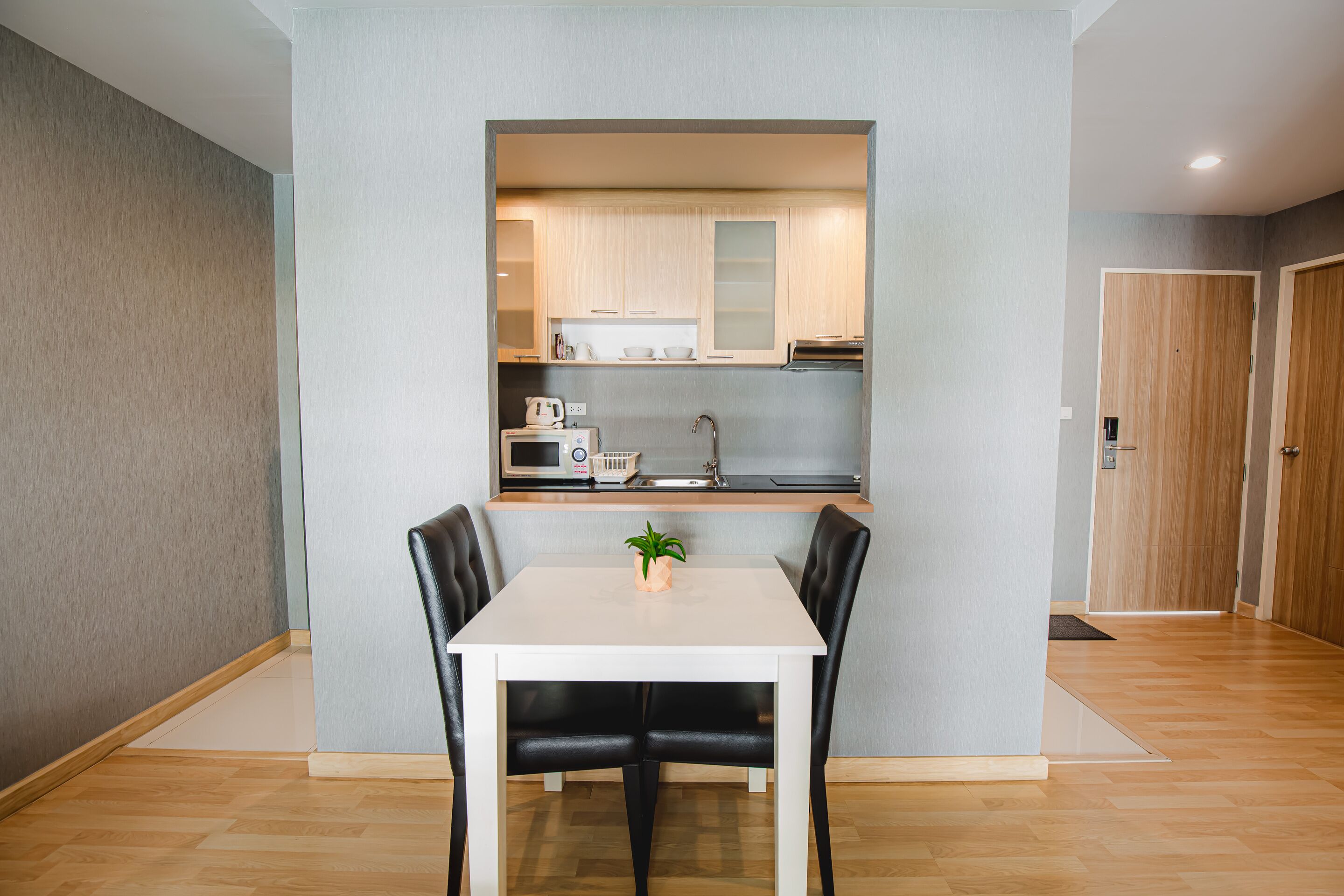 A modern kitchen with white cabinets, a microwave, and a sink.
