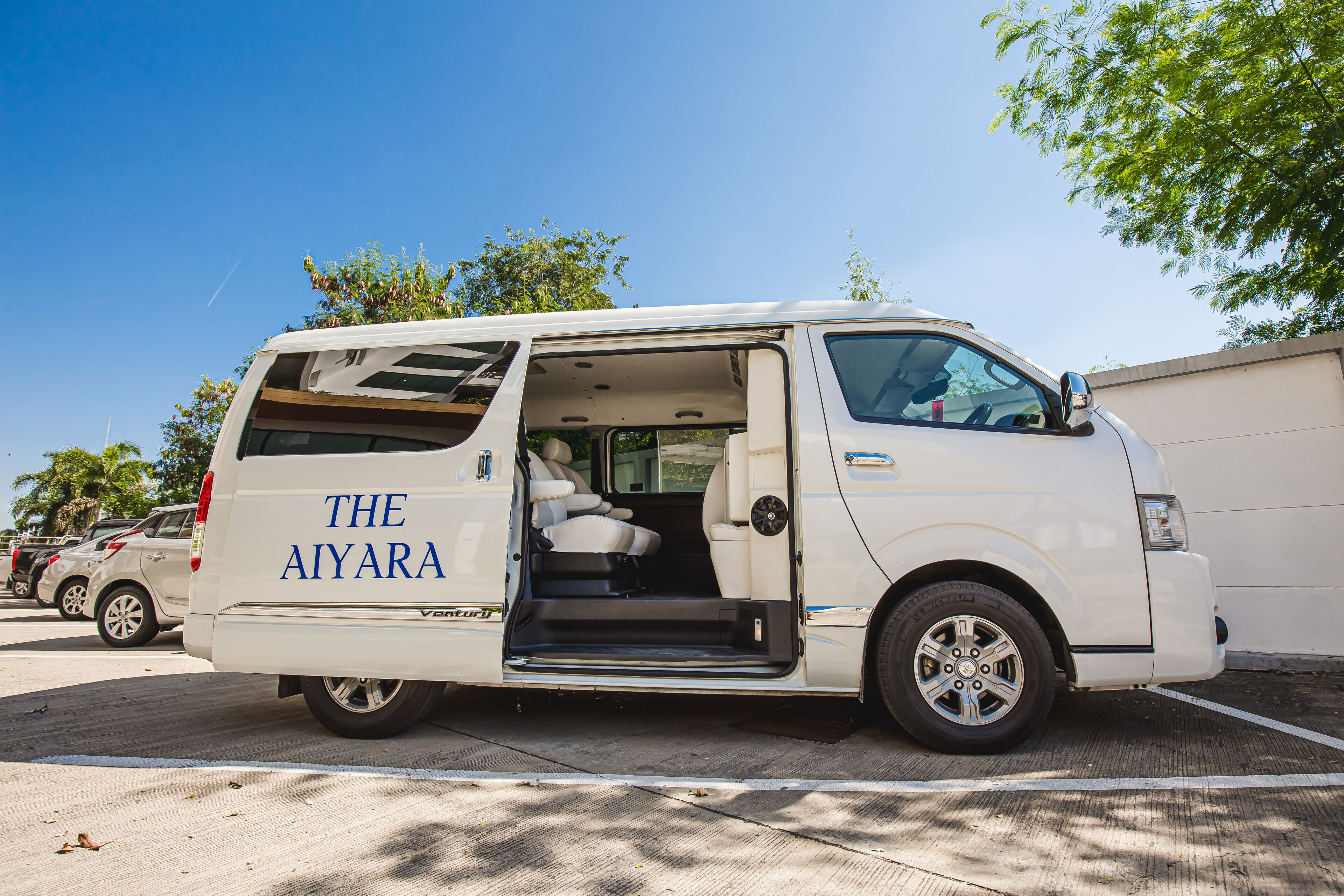 Ein weißer Van mit dem Aufdruck "THE AIYARA" steht auf einem Parkplatz.