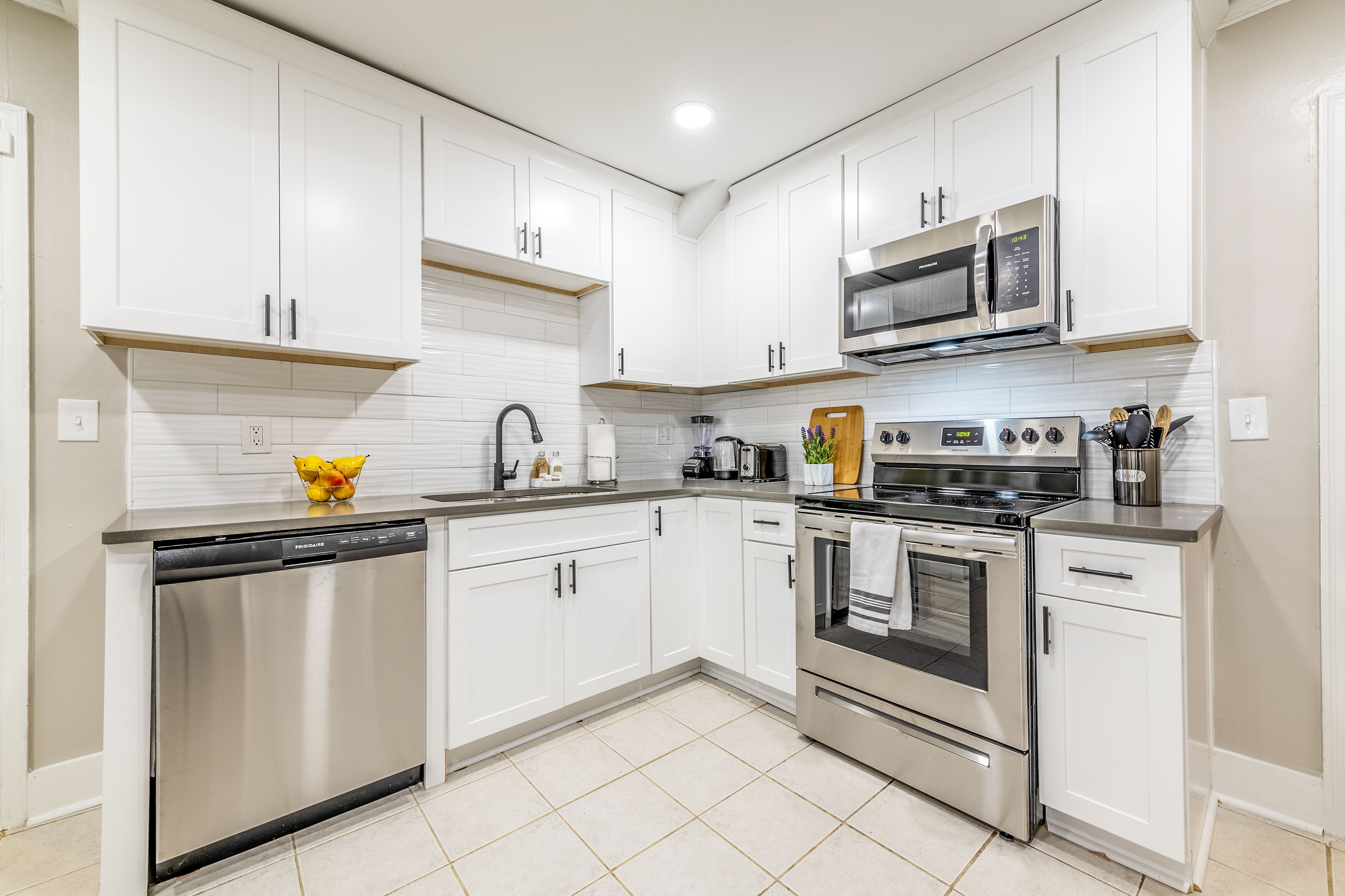 A modern kitchen with white cabinetry, stainless steel appliances, and a tiled backsplash.