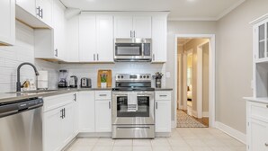 A modern kitchen with white cabinets, stainless steel appliances, and a tiled floor. - Charming entire house only 5 miles from Truist Park. (Smyrna)