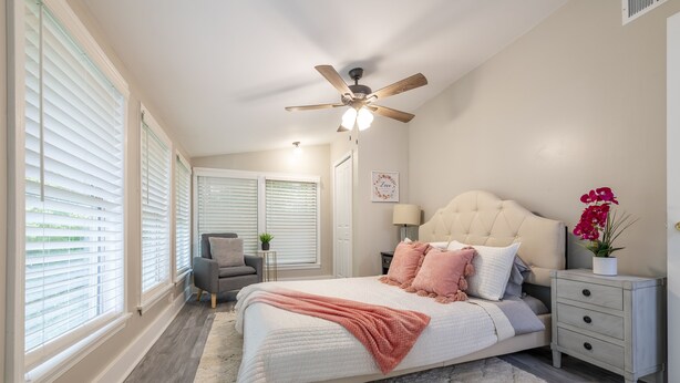 A bedroom with a bed, nightstands, a ceiling fan, and a window with blinds. - Charming entire house only 5 miles from Truist Park. (Smyrna)