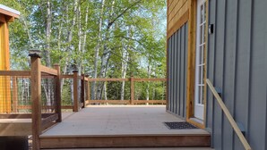 A wooden staircase leading to a deck with a metal railing, surrounded by trees.