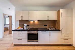 A modern kitchen with white cabinets, a black countertop, and a built-in oven.