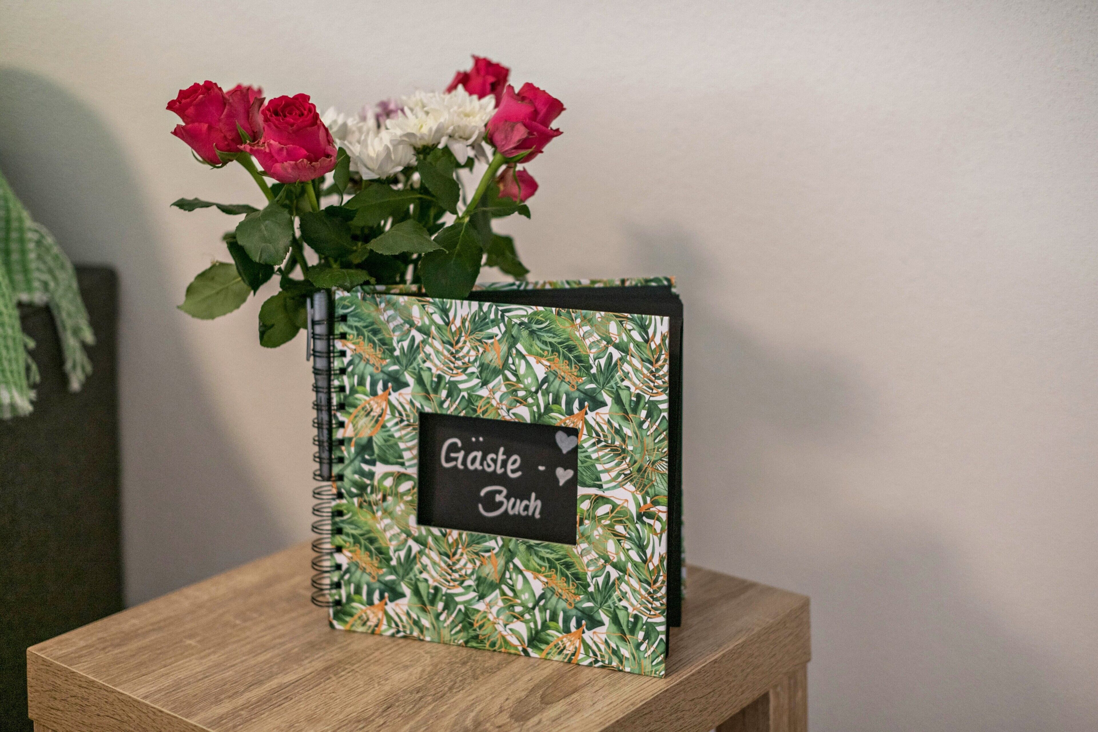En notesbog med et blomstermønster og en etiket med teksten 'Gäste Buch'.
