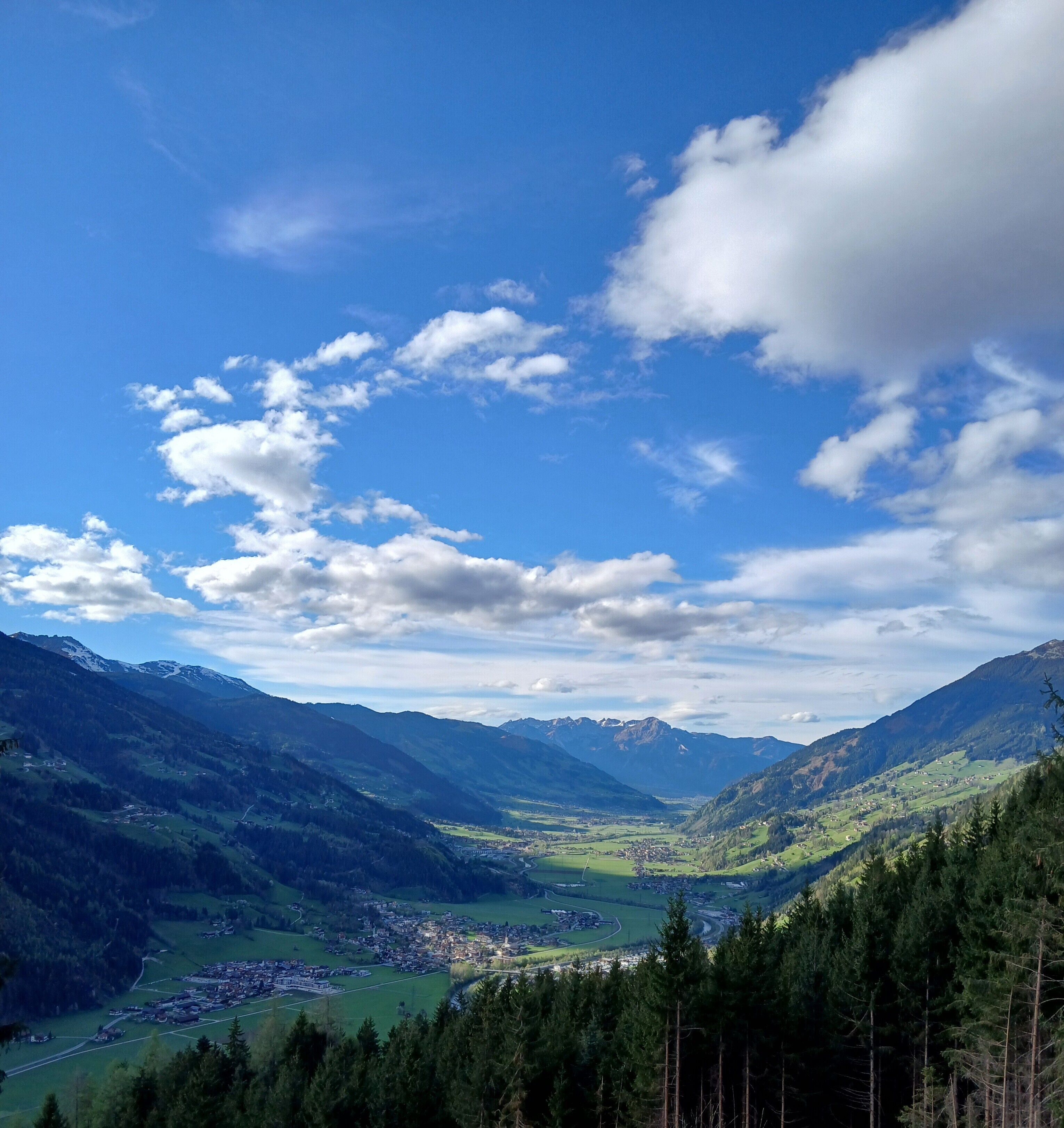 Eine gebirgige Landschaft mit einem Tal, einer Stadt und einem klaren Himmel.