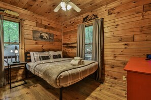Une chambre à coucher dans un chalet en bois, avec un lit, une table de chevet, une lampe et une horloge fixée au mur.