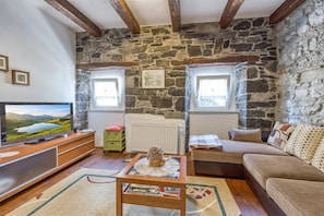 A cozy living room with stone walls, a wooden TV stand, a sofa, and a coffee table.