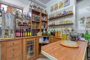 A well-stocked liquor store with shelves of various bottles and jars, a wooden counter with glasses, and a decorative pitcher.