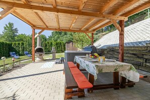 An outdoor patio with a wooden pergola, a barbecue grill, a table with a tablecloth, and a bench. - Ladybug House Nature Retreat w/ Jacuzzi, Fokovci, Slovenia (Fokovci)