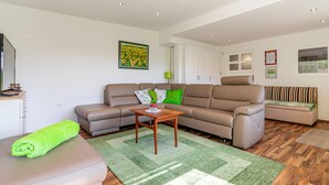 Un salon moderne avec un canapé, une table basse et une serviette vert vif posée sur un banc rembourré.