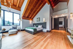 Camera da letto moderna con un letto grande, una poltrona e vista sull'esterno tramite ampie finestre.