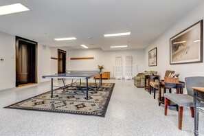 Ein modernes Interieur mit Tischtennisplatte, einem gemusterten Teppich und einer Sitzecke mit Sofa und Sesseln.