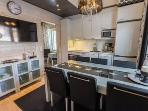 A modern kitchen with a central island, white cabinetry, and a chandelier.