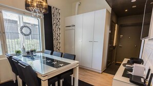 Uma cozinha moderna com armários brancos, uma mesa de jantar de vidro e um lustre.