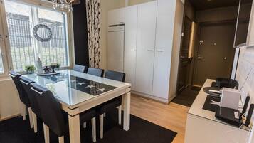 A modern kitchen with white cabinets, a glass dining table, and a chandelier.